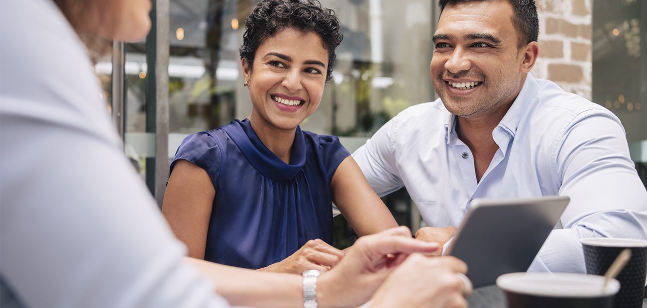 Smiling couple with agent at cafe table