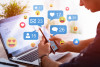 Social media like and share icons floating over hands using laptop & smart phone