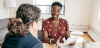 Two women sitting in an office talking with one another
